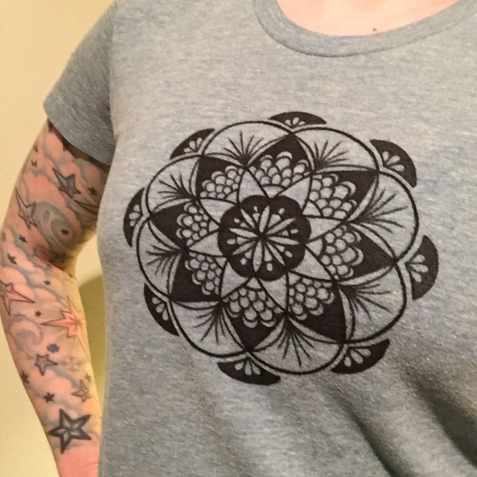 Hand drawn black fan mandala on a teal shirt in full view